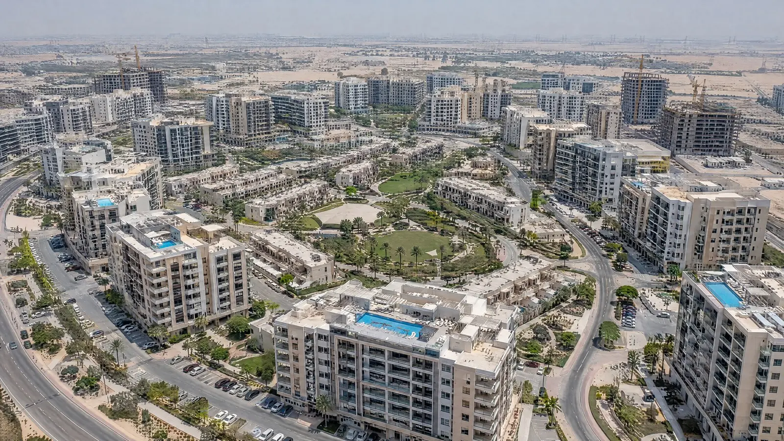 מבט אווירי על קהילת מגורים בדובאי עם בנייני דירות, פארק וכבישים מעגליים, שוק הנדל״ן בדובאי 2026